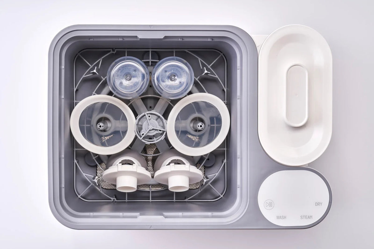 A standard breast pump set and two bottles loaded together in the nuviebaby Clean Max washing basin, seen from above.